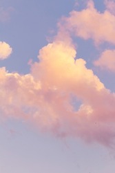 Vertical shoot.Light pink clouds in sunset blue sky. Pastel colors of clouds, sunrise sundown natural background.Pink purple clouds in blue sky while sunset twilight magic happening in nature, defocus