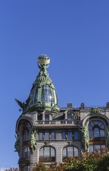 tower with dome topped sculptural composition and glass globe, art nouveau architecture features on blue sky background with shallow depth of field. Singer or Book House on Nevsky Prospect