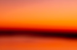 abstract pink orange blurred background with dark stripe on horizon. Blur pastel colored sweet dreamy background. Pink orange bokeh out of focus natural sky sunset background