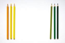 Six color pencils, two yellow, one orange, three green in a row, with a white space in the middle for copy writing
