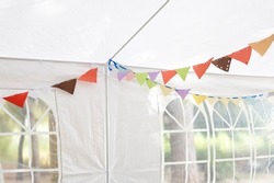 Red, orange, green, brown party flags made by children for their birthday party, and set in a tent