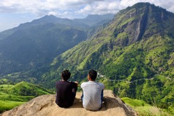 two young man enjoy scenic view of mountain landscape at little adam's peak, sri lanka. back to viewer