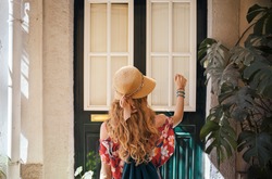 Blonde woman wearing generic red dress and a hat is knocking the door