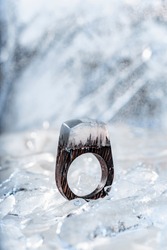 Wooden jewlery which is ring with resin top on the backghround made with ice