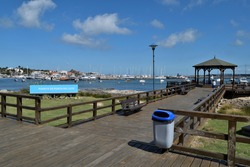 Photography of a wooden pier and a gazebo and the yacths anchored at  the port of Punta del Este City, Uruguay and a sign saying Port of Punta del Este in spanish