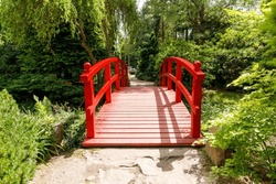 Japanese style red bridge in a naturalistic garden