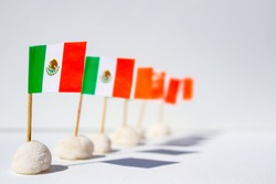Row of mini Mexican flags in a row with interesting shadows - shallow depth of field with front one in sharp focu against white background