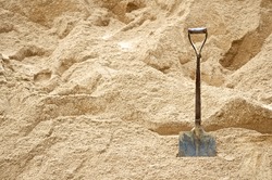 Steel shovel be used for scoop sand to construct the building background, front view.