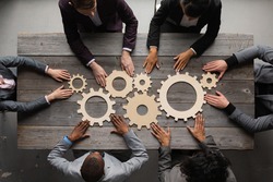 Business people connect golden gear together at meeting table, success cooperation teamwork concept