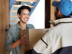 It got here so fast. Shot of a smiling young woman standing at her front door receiving a package from a courier.