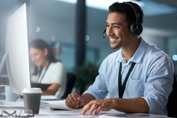 Where would we be without loyal customers like you. Shot of a young man using a headset and computer in a modern office.