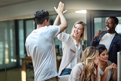 Weve done it again. Shot of a group of colleagues giving each other a high five while using a computer together at work.
