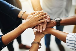 Together, anything is possible. Closeup shot of a group of unrecognizable businesspeople joining their hands together in a huddle.