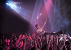 Surfing on a wave of praise. A stage diver being carried across the audience at a rock concert.