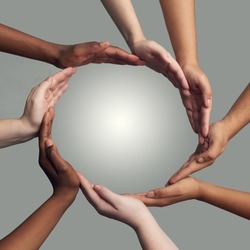 Coming together to form one. Cropped shot of a group of hands linking together to form a circle against a grey background.