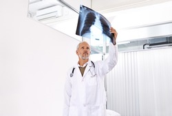 Checking out your ribcage. Shot of a mature male doctor examining an x-ray image at a hospital.