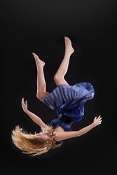 Sometimes you have to fall to know where you stand. Studio shot of a woman falling upside down against a black background.