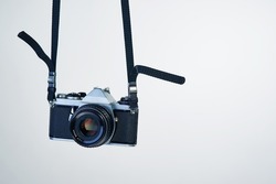 Film photography makes a comeback. Studio shot of a camera hanging by its strap.