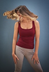 Let it all hang out. Shot of a young woman twirling her hair against a gray background.