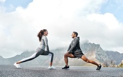 Stretch well to increase your speed and stride. Shot of a sporty young man and woman stretching their legs while exercising outdoors.