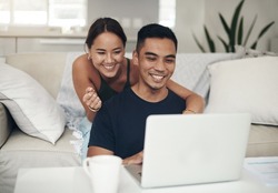 They found something interesting online. Shot of a young couple using a laptop together at home.
