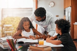 Set a regular schedule for completing homework. Shot of a dad helping his children with their homework.