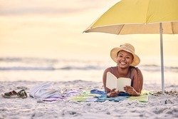 Serenity that speaks volumes. Portrait of a beautiful young woman relaxing with a book at the beach.