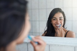 Taking care of her pearly whites. Shot of an attractive young woman brushing her teeth in the bathroom.