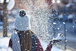 She turns snow into glitter. Rearview shot of a young woman throwing snow on a wintery day outdoors.