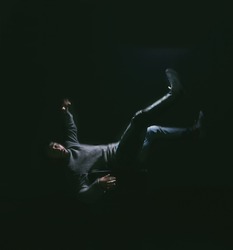 Falling your dream Thats fear of losing control. Shot of a young man falling against a dark background.