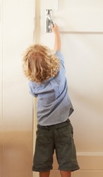 Help your child open the door to a promising future. Rear-view a toddler boy reaching up to open a door.