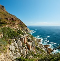 Landscape view of mountains surrounded by ocean in Hout Bay in Cape Town, South Africa. Beautiful popular tourist attraction of scenic hills and calm blue water. Exploring nature and the wild