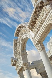 Historical Turkey Ephesus arch in an ancient city. Closeup of a keystone arch with architectural detail and patterns. Ruin of ancient roman archway temple outside under a blue sky with light clouds