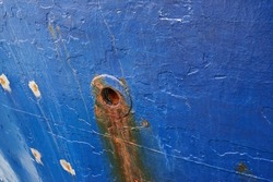 Abandoned and rusty limber hole on the side of docked ship outside. Closeup of rust stained hawsehole used for draining water on the hull of a nautical boat in a dockyard and port overseas and abroad