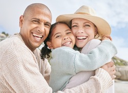 Portrait of happy interracial family on vacation in summer. Smiling and laughing parents bonding with their daughter outside and having fun on the beach. Cute little girl embracing her mom in a hug