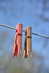 Plastic material decay, crack and discoloration on household objects caused by UV radiation. Closeup details of old pegs on a clothing line outdoors against blurred background with copy space