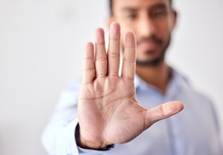 Closeup of the hand of a business man showing stop, saying no or not accepting a deal in an office at work. Male corporate worker making hand gesture not agreeing to a statement or refusing an