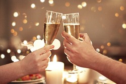Cheers, toast and celebration with a couple on a romantic date for their engagement, anniversary or honeymoon. A candle lit dinner with wine glasses in the hands of a man and woman in a restaurant