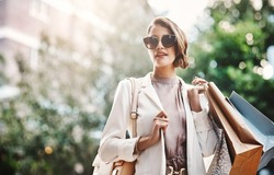 Trendy, fashionable and elegant woman enjoying shopping in the city. Young female coming from a sale downtown, holding shopping bags while looking satisfied. Lady spending the day on retail therapy