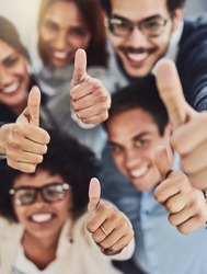 Thumbs up from a happy business team excited about the success they achieve together at work. Overhead view diverse group of corporate people excited by success and give approval to winning