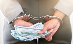 . Handcuffs, dollars and a business woman arrested for theft at work. Money, crime and punishment for fraud with female lawyer in prison. Cash, restraints and a criminal trying to bribe an officer.