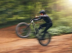 Freedom, energy and bike with adrenaline cyclist training in nature, practice extreme jumping trick on dirt road. Fitness, bicycle and action by sports man enjoy intense activity, control and speed