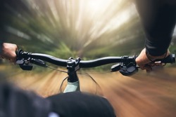 Hands, man and cycling skills while on a bicycle outdoor in a forest. Adrenaline junkie practice, training or race fast in extreme sports on bike with endurance and cardio during a off road training