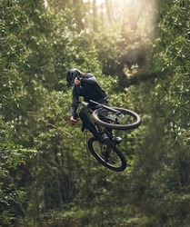 Cycling, bicycle jump and sports man travel in Japan nature forest for adventure and extreme sport journey. Trees, stunt and mountain bike rider or cyclist training in woods for exercise and fitness