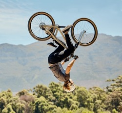Mountain bike, man and upside down air jump, action and bicycle stunt, challenge and adventure, freedom or dynamic risk in sky. Biker athlete, sports adrenaline and energy in outdoor competition show