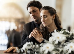 Sad, funeral and flowers with couple and coffin in church for death, respect and mourning. Grief, goodbye and empathy with man and woman loss at casket with depression, remember and farewell memorial