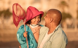 Father, fishing and child on beach for freedom, love and learning to fish in summer together. Excited kid, happy family and teaching girl with fishing net on holiday adventure or vacation outdoor