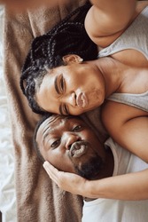 Black couple, love and bedroom selfie while happy and funny together, pouting on bed at home, apartment or hotel. Portrait of a young man and woman in a happy marriage with commitment in top view