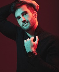 Man, fashion portrait and studio with red light for clothes, beauty and luxury style on dark background. Face of aesthetic model person with turtle neck, art and cosmetics for inspiration for men
