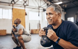 Training, senior and man exercise with personal trainer at the gym squat with kettlebell equipment for strength. Elderly, old and fitness people workout in a health club for wellness and motivation